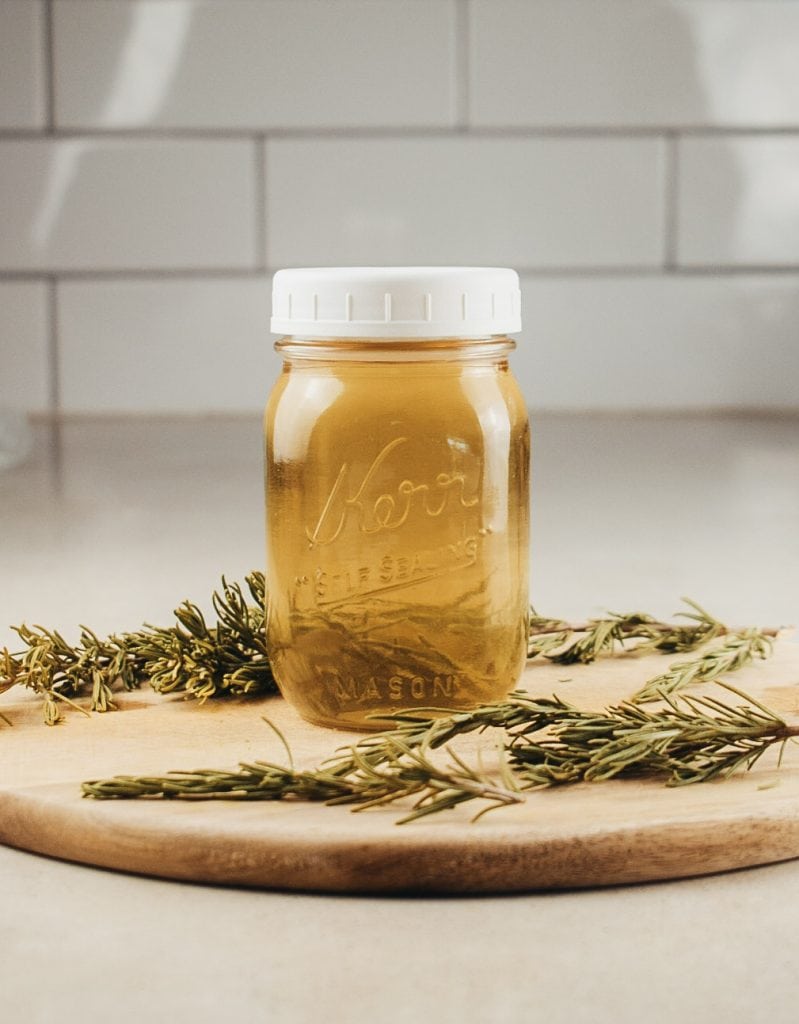 A mason jar full of rosemary water for hair growth on the kitchen counter.