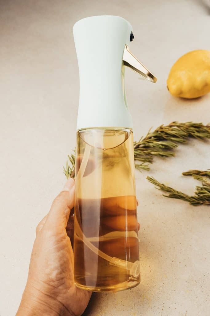 A person holding a bottle of DIY rosemary water for hair growth.