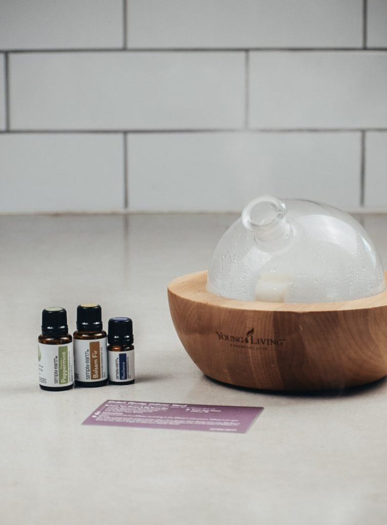 Essential oils next to an essential oil diffuser on the kitchen counter.